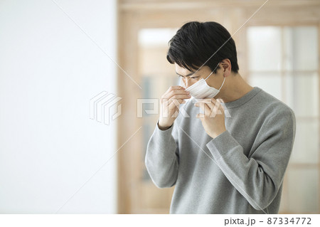部屋でマスクを付ける30代の男性 部屋でマスクを付ける30代の男性 87334772