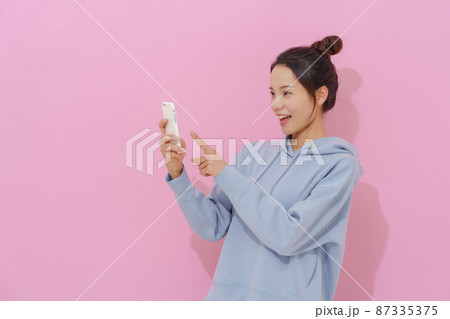 スマホを持つ女性 ピンク背景 スマホを持つ女性 ピンク背景 87335375