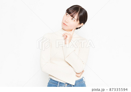 白背景の前に立って悩んでいるカジュアルな服装の女性 白背景の前に立って悩んでいるカジュアルな服装の女性 87335594