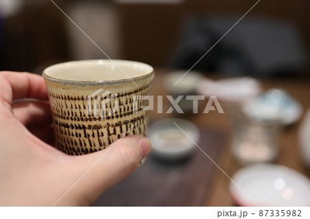 居酒屋でぐい吞みでお酒を飲む 87335982