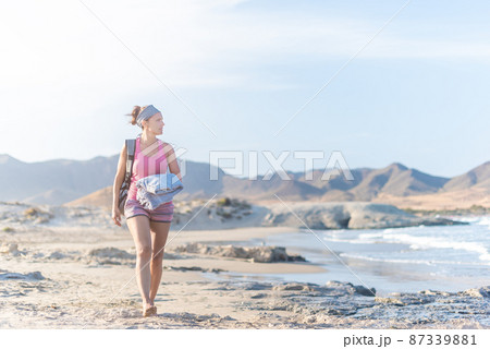 Relaxed woman walking on sandy beach near sea Relaxed woman walking on sandy beach near sea 87339881