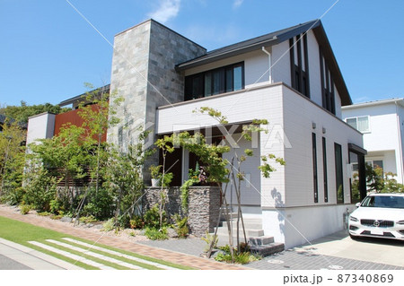 青空に映える白亜の壁と石張りのアクセントウォールが美しい高級感のある瀟洒でスタイリッシュな戸建て住宅 87340869