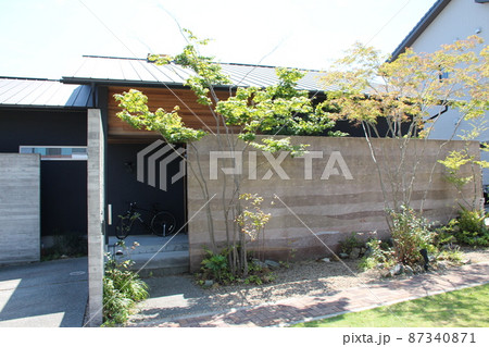 アースカラーのグラデーションが美しい塀と黒色と木板張りのシックでモダンでスタイリッシュな平屋の住宅 87340871