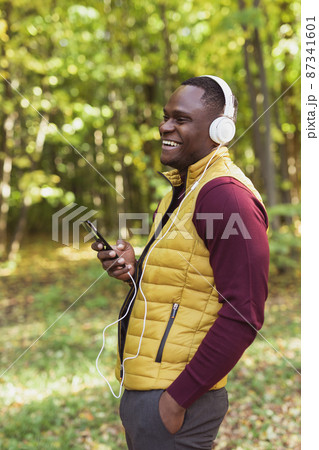 African american man listens music in spring park. Gadget, app and streaming service concept 87341601
