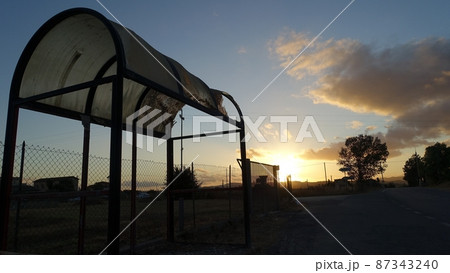 A half-destroyed bus stop in a suburban area at sunset A half-destroyed bus stop in a suburban area at sunset 87343240