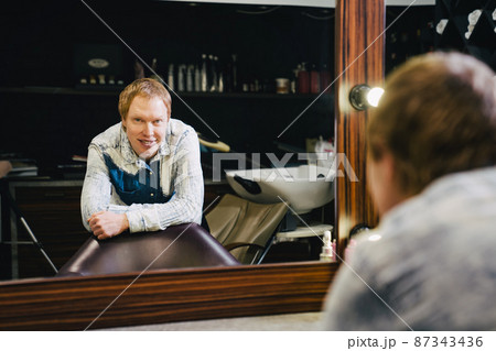 male hairdresser and stylist barbershop worker reflected in the mirror. male hairdresser and stylist barbershop worker reflected in the mirror. 87343436