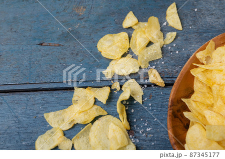 Directly above shot of potato chips with salt on wooden table Directly above shot of potato chips with salt on wooden table 87345177