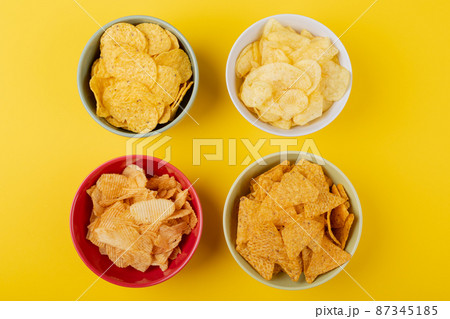 Directly above shot of various snacks in bowls on yellow background 87345185