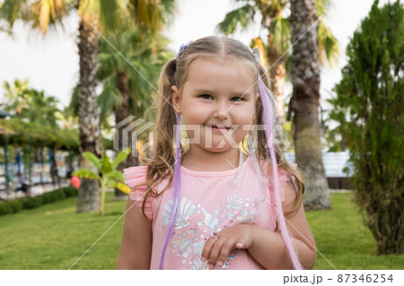 Portrait of a cute girl 4 years old dressed in a multi colored dress against the background of palm Portrait of a cute girl 4 years old dressed in a multi colored dress against the background of palm 87346254