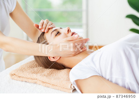 Young woman enjoying of facial massage in spa salon 87346950