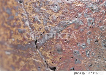 激しく荒々しい炎の影響を受けた溶岩のような辰砂色を見せる陶器の肌面のテクスチャー写真。 激しく荒々しい炎の影響を受けた溶岩のような辰砂色を見せる陶器の肌面のテクスチャー写真。 87346960