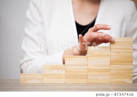 Fingers climbing the stairs made with wooden blocks. 87347416