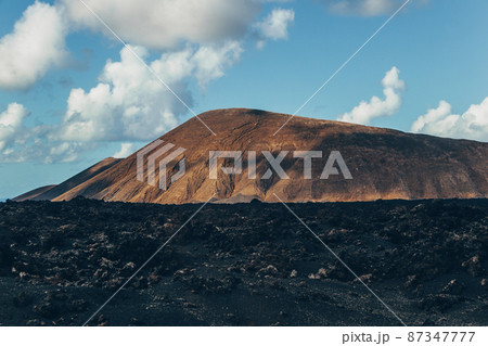 Amazing panoramic landscape of volcano craters in Timanfaya national park. Popular touristic attraction in Lanzarote island, Canary islans, Spain. Artistic picture. Beauty world. Travel concept. Amazing panoramic landscape of volcano craters in Timanfaya national park. Popular touristic attraction in Lanzarote island, Canary islans, Spain. Artistic picture. Beauty world. Travel concept. 87347777