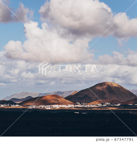Amazing panoramic landscape of volcano craters in Timanfaya national park. Popular touristic attraction in Lanzarote island, Canary islans, Spain. Artistic picture. Beauty world. Travel concept. Amazing panoramic landscape of volcano craters in Timanfaya national park. Popular touristic attraction in Lanzarote island, Canary islans, Spain. Artistic picture. Beauty world. Travel concept. 87347791