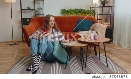 Smiling happy young woman counting money cash and use mobile phone calculate domestic bills at home 87348678