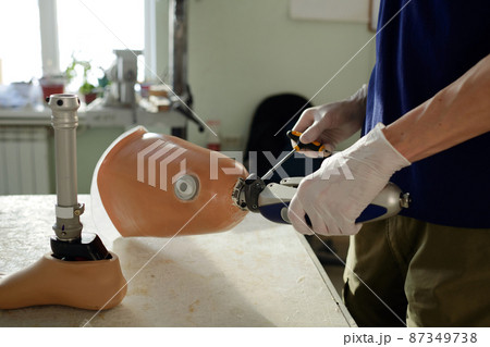 Gloved hands of manual worker fixing mechanism with screwdriver 87349738