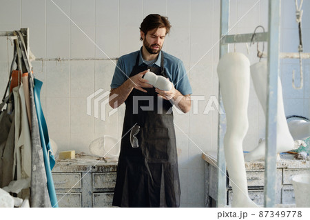 Young master of prosthetic manufactory looking at plaster cast Young master of prosthetic manufactory looking at plaster cast 87349778