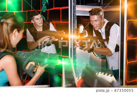 Two laser tag teams playing enthusiastically and aiming at each Two laser tag teams playing enthusiastically and aiming at each 87350055