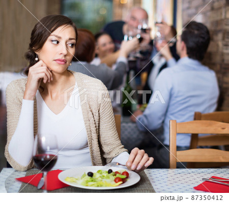 Portrait of upset woman in the restaurant with salad and wine Portrait of upset woman in the restaurant with salad and wine 87350412