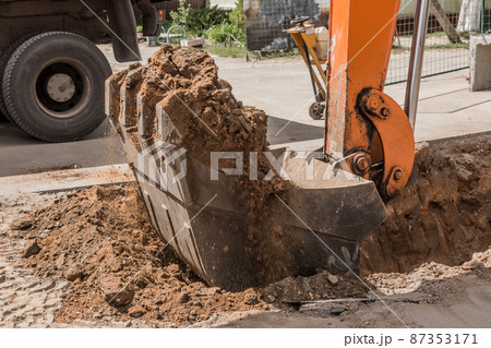 Excavation works. Tractor bucket digging with a heavy shovel on the ground at the construction site 87353171