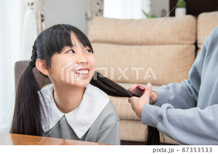 娘の髪の毛を結ぶ母親 87353533