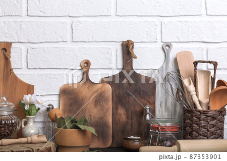 Kitchen utensils and spices on a kitchen countertop against a white brick wall. Food background with wooden eco friendly utensils. Front view Kitchen utensils and spices on a kitchen countertop against a white brick wall. Food background with wooden eco friendly utensils. Front view 87353901