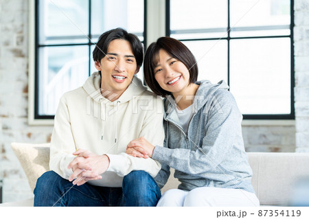 リビングでくつろぐ若い夫婦 リビングでくつろぐ若い夫婦 87354119
