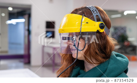 A woman in a helmet synchronizing her gaze and the movement of a computer mouse.  87354529