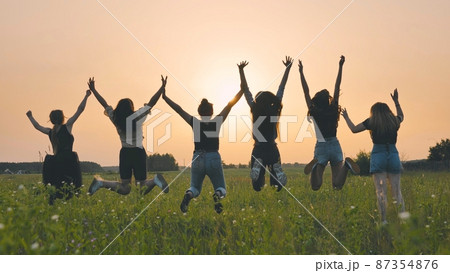 Girls friends are jumping against the background of an evening summer sunset. Girls friends are jumping against the background of an evening summer sunset. 87354876