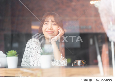 窓越しに見えているカフェの若い女性 87355099