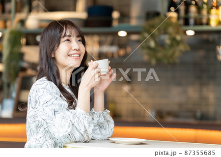 カフェでコーヒーを飲んでいる若い女性 カフェでコーヒーを飲んでいる若い女性 87355685