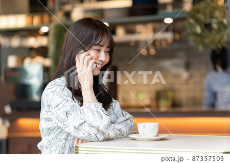 カフェで電話している若い女性 87357503