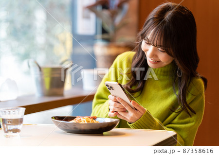 カフェでパスタの写真を撮っている若い女性 カフェでパスタの写真を撮っている若い女性 87358616