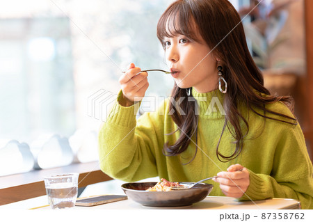 カフェでパスタを食べている若い女性 87358762