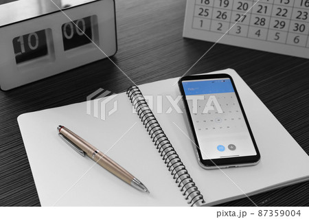 Modern smartphone with calendar on screen in office 87359004
