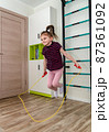 A little girl goes in for sports in her room. 87361092