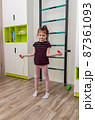 A little girl goes in for sports in her room. 87361093