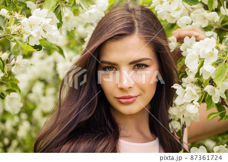 Romantic woman with perfect windy brown hair in spring flowers garden Romantic woman with perfect windy brown hair in spring flowers garden 87361724