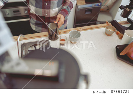 Photo of male barista hands holding pitcher with milk Photo of male barista hands holding pitcher with milk 87361725