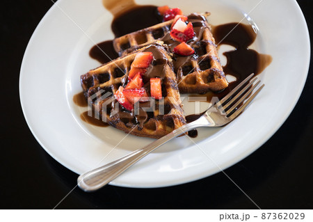 Waffles with chocolate syrup and strawberries Waffles with chocolate syrup and strawberries 87362029