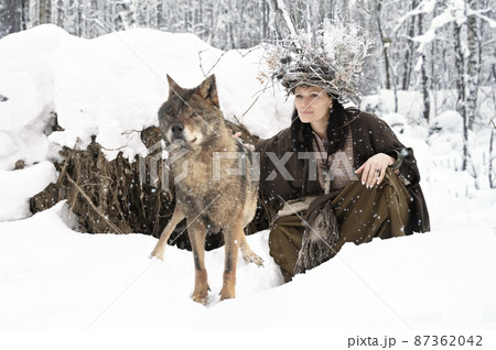 Female forest dweller with a big gray wolf in the winter forest 87362042