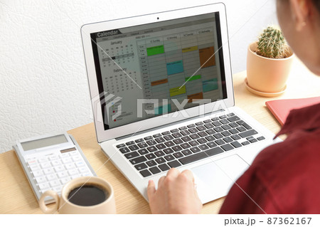 Woman using calendar app on laptop in office, closeup 87362167