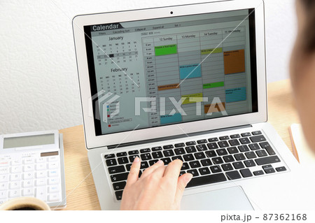 Woman using calendar app on laptop in office, closeup 87362168