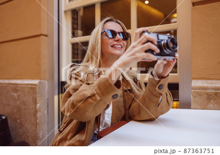 Smiling woman tourist sitting at the table outside Smiling woman tourist sitting at the table outside 87363751