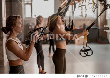 Group of young fitness people using fitness straps in sports club 87363752