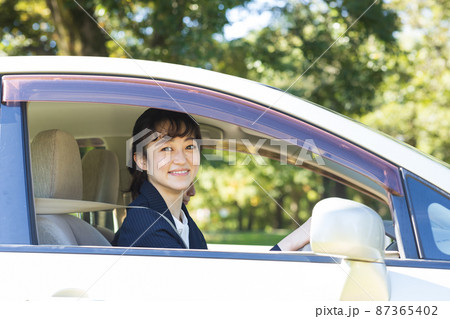 スーツを着て車を運転する女性 87365402