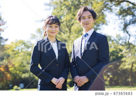 屋外に立つスーツを着た男女 87365683