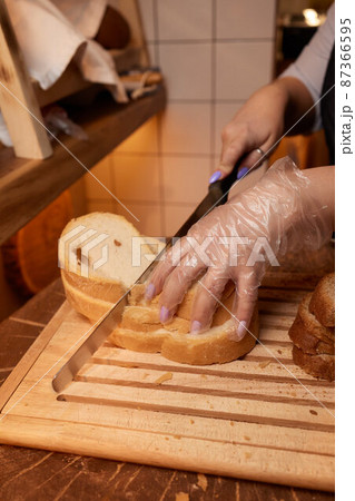 Male hands cutting wheaten bread on the wooden board, selective focus. Male hands cutting wheaten bread on the wooden board, selective focus. 87366595