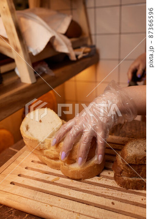 Male hands cutting wheaten bread on the wooden board, selective focus. 87366596