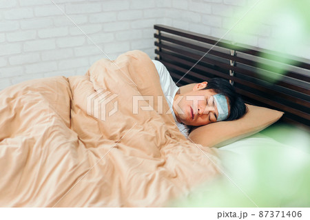 風邪をひいてベッドで寝る男性 87371406